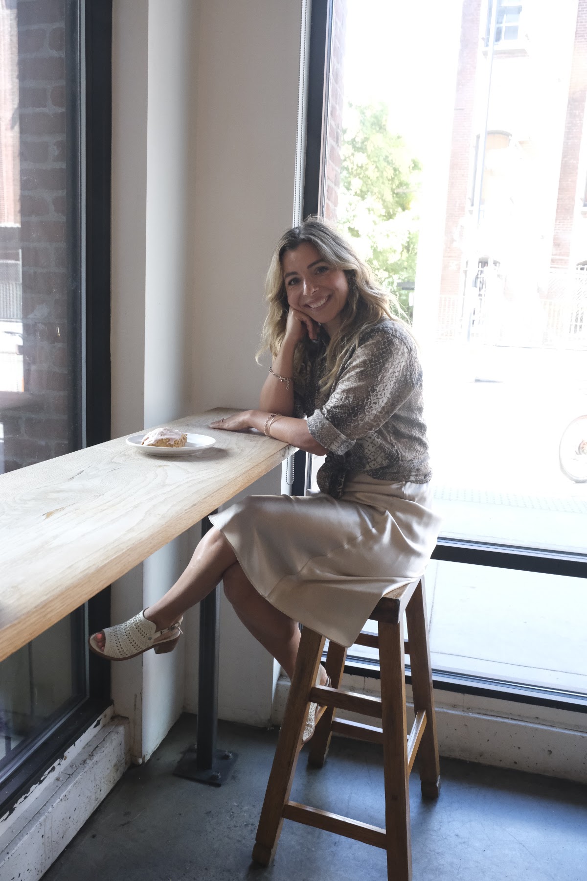Simone seated by a café window