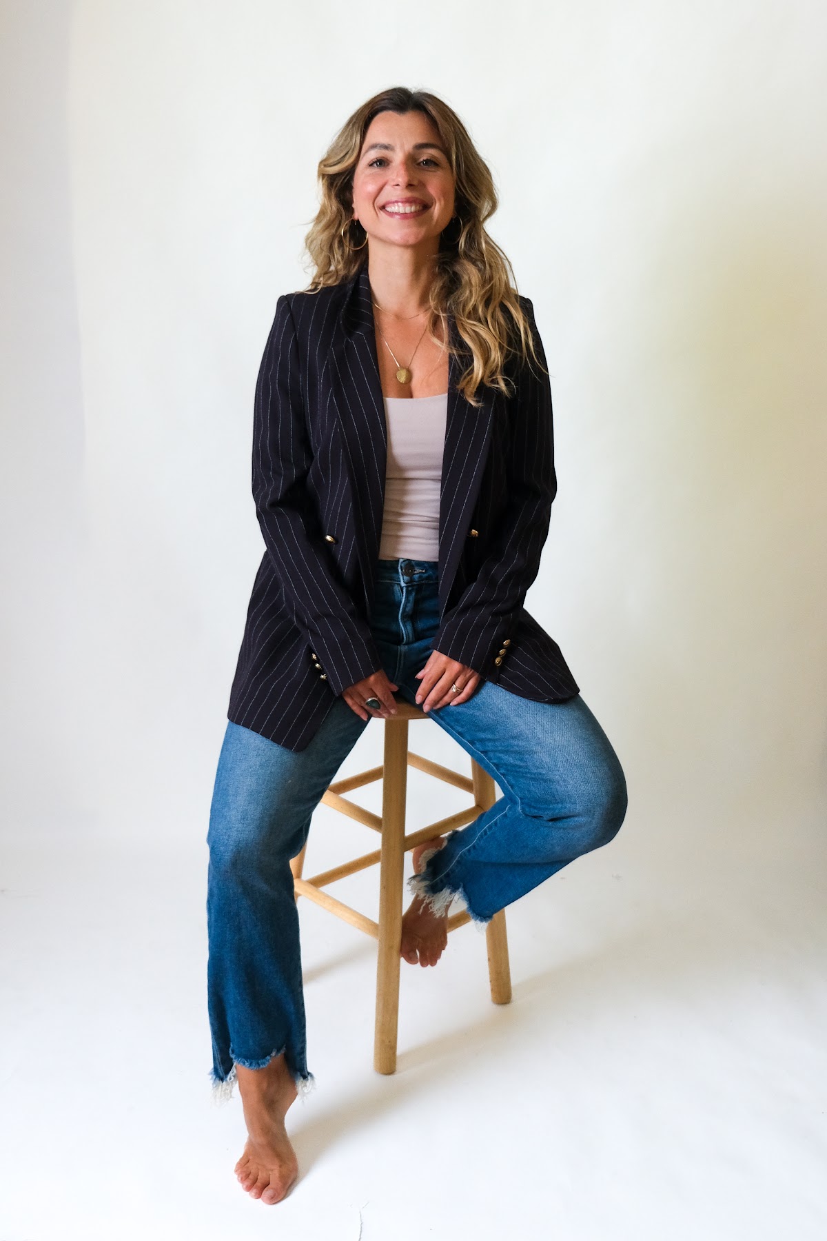 Simone in a blazer, seated on a stool